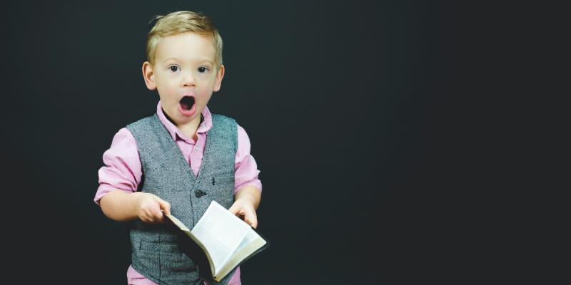 Small boy holding a book looking surprised. Photo by Ben White on Unsplash